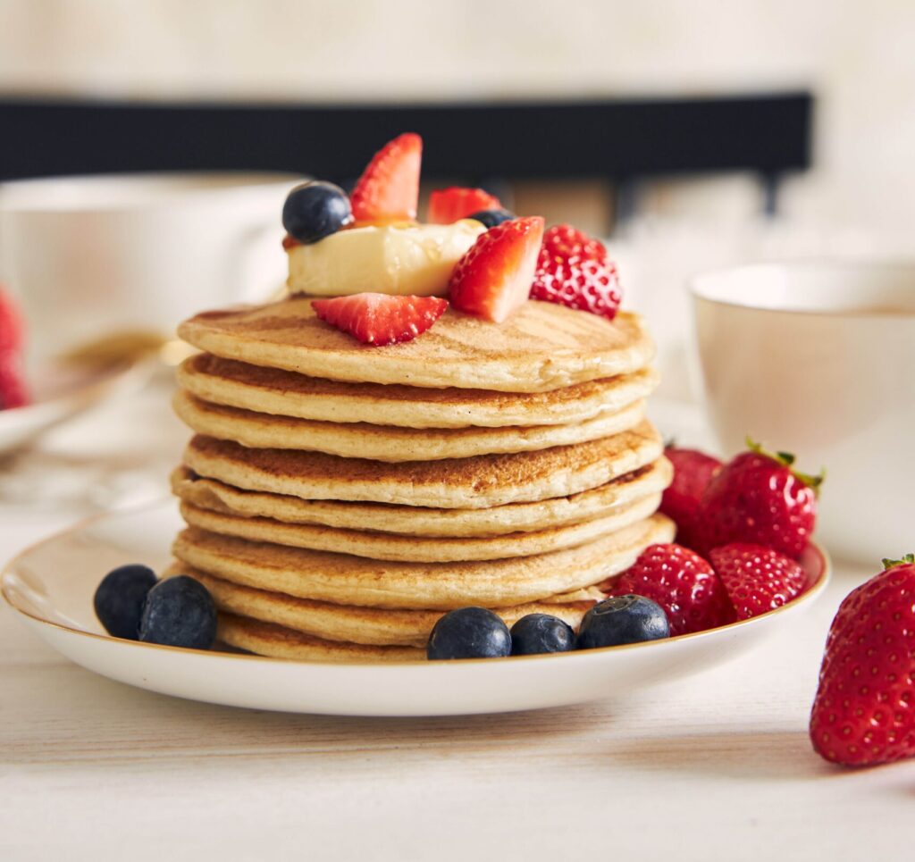 Tortitas de avena saludables con frutas frescas como arándanos y fresas, presentadas en un plato sobre una mesa de madera, un desayuno nutritivo ideal para un estilo de vida saludable.