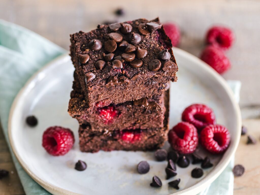 Brownie de chocolate saludable servido en un plato blanco, acompañado de frutos rojos frescos, ideal para una dieta equilibrada recomendada por nuestra consulta nutricional en L'Hospitalet de Llobregat, Barcelona.