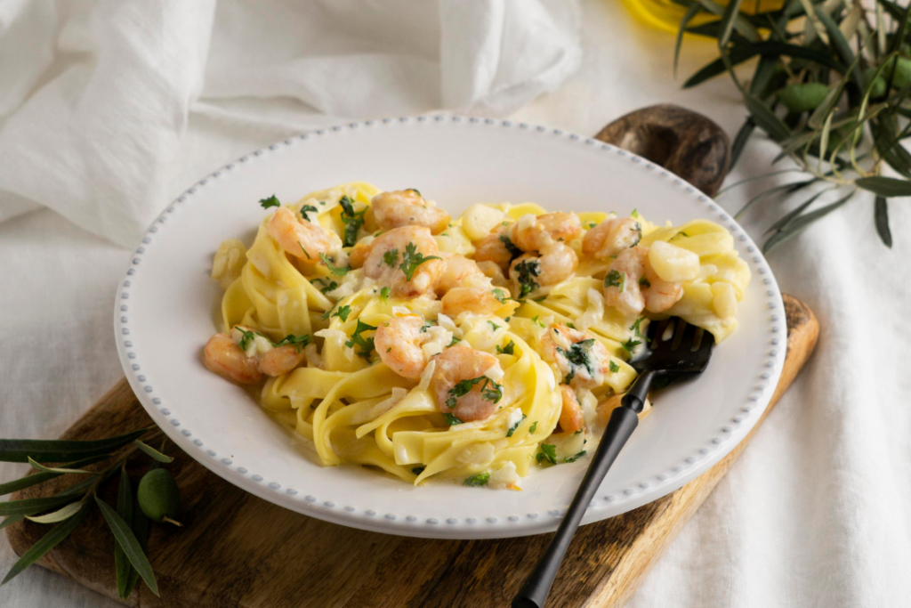 Plato de pasta cremosa con gambas y salsa de curry decorado con perejil, receta saludable.